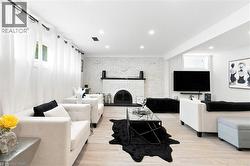 Living area featuring a painted brick fireplace with a black mantel, recessed lighting, and wood-finish flooring - 