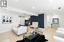 Open-concept living area featuring light wood-finish flooring, recessed lighting, and a modern accent wall with geometric paneling - 