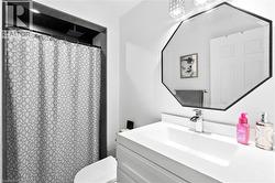 White vanity with an integrated rectangular sink, chrome single-handle faucet, and an octagonal mirror with a black frame - 