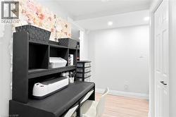Dedicated workspace featuring a built-in black desk with integrated shelving, recessed lighting, light wood-finish flooring, and a white paneled door - 