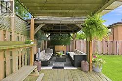 Spacious wood deck featuring an integrated pergola structure, a slatted privacy fence with lattice accents, and a large grassy yard area - 