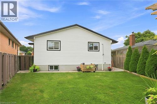 Expansive rear yard featuring a manicured lawn, a concrete patio area, and mature evergreen plantings - 15 Quay Court, Hamilton, ON - Outdoor With Exterior