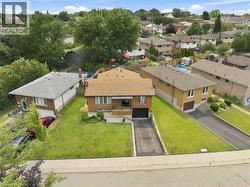 Brick exterior residence featuring a front yard with established landscaping and a paved driveway - 