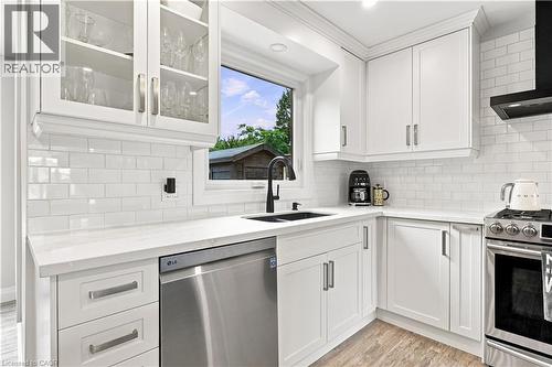 Kitchen featuring white shaker-style cabinetry, a white subway tile backsplash, light-toned countertops, a stainless steel dishwasher, and a black sink with a matte black faucet - 10 Rolling Acres Drive, Kitchener, ON - Indoor Photo Showing Kitchen With Double Sink With Upgraded Kitchen