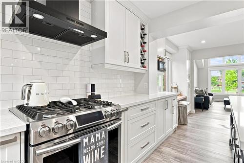 Modern kitchen featuring white cabinetry, subway tile backsplash, stainless steel gas range, and a built-in wine rack - 10 Rolling Acres Drive, Kitchener, ON - Indoor Photo Showing Kitchen With Upgraded Kitchen