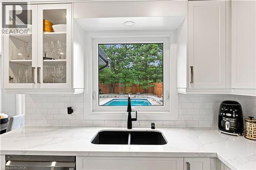 White shaker-style cabinetry with glass-front accents, white subway tile backsplash, and a black undermount sink with a matte black faucet - 10 Rolling Acres Drive, Kitchener, ON - Indoor Photo Showing Kitchen With Double Sink