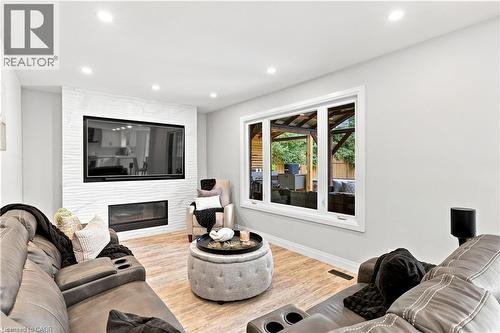 Living area featuring recessed lighting, light wood-finish flooring, a contemporary fireplace with a decorative textured surround, a large window, and light-toned wall paint - 10 Rolling Acres Drive, Kitchener, ON - Indoor Photo Showing Living Room With Fireplace