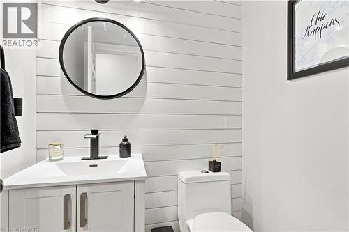 Modern powder room featuring white shiplap walls and a contrasting matte black round mirror - 10 Rolling Acres Drive, Kitchener, ON - Indoor