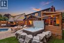 Expansive backyard featuring an in-ground pool with paved surround, hot tub with rock border, dedicated outdoor kitchen structure, and a covered grilling area - 10 Rolling Acres Drive, Kitchener, ON  - Outdoor With In Ground Pool With Deck Patio Veranda 