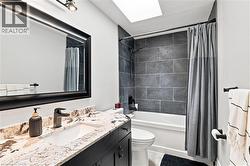 Bathroom featuring a vanity with a stone countertop, an undermount sink, and dark cabinetry - 