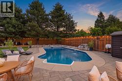 Expansive backyard featuring a custom-shaped inground pool with water features, surrounded by multi-tone paver and concrete decking - 
