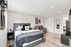 Spacious bedroom with wood-finish flooring, recessed lighting, white walls, and bi-fold closet doors - 