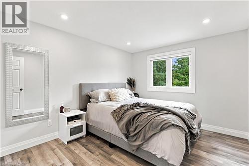 Recessed ceiling lighting illuminates this space featuring wood-finish flooring, white baseboards, and a window with white trim - 10 Rolling Acres Drive, Kitchener, ON - Indoor Photo Showing Bedroom