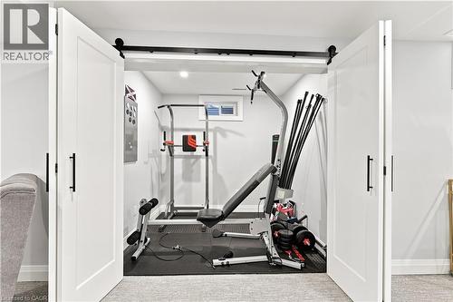 Dedicated exercise space featuring white barn doors with black hardware, a high transom window, light gray walls, and dark rubber flooring - 10 Rolling Acres Drive, Kitchener, ON - Indoor Photo Showing Gym Room
