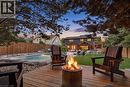 Expansive backyard featuring a wood-finish deck with a fire pit, a rectangular swimming pool, and a manicured lawn - 10 Rolling Acres Drive, Kitchener, ON  - Outdoor With Deck Patio Veranda 