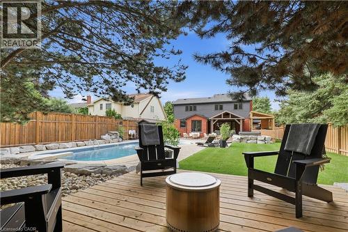 Expansive backyard featuring a wood deck, swimming pool, and stone retaining walls - 10 Rolling Acres Drive, Kitchener, ON - Outdoor With Deck Patio Veranda With Backyard