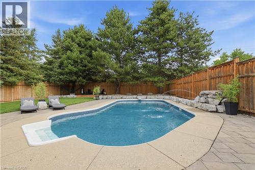 In-ground swimming pool featuring a curved design, integrated steps, and a decorative water feature - 10 Rolling Acres Drive, Kitchener, ON - Outdoor With In Ground Pool With Deck Patio Veranda With Backyard