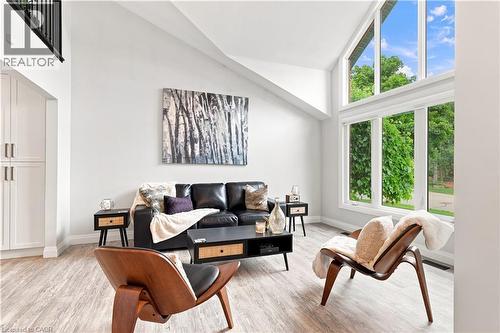 Living space featuring a soaring vaulted ceiling, expansive multi-paned windows, light wood-finish flooring, and built-in white cabinetry - 10 Rolling Acres Drive, Kitchener, ON - Indoor Photo Showing Living Room