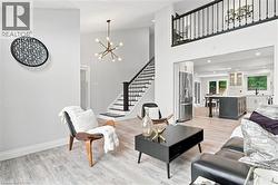 Spacious interior featuring wood-finish flooring, a contemporary chandelier, and an open concept layout with a kitchen - 