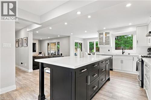 Contemporary kitchen featuring a large island with dark cabinetry, light countertops, integrated sink, stainless steel appliances, and light wood-finish flooring - 10 Rolling Acres Drive, Kitchener, ON - Indoor Photo Showing Kitchen With Upgraded Kitchen