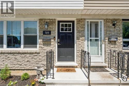Stone veneer facade featuring a black paneled door with window inserts, white window frames, and decorative wrought iron railings - 589 Elgin Street N, Cambridge, ON - Outdoor
