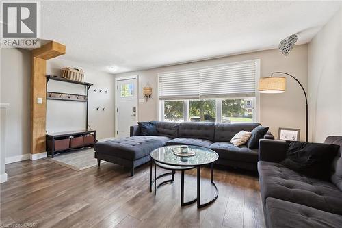 Bright living area featuring wood-finish flooring, a large multi-pane window, and a white entry door with glass inserts - 589 Elgin Street N, Cambridge, ON - Indoor Photo Showing Living Room