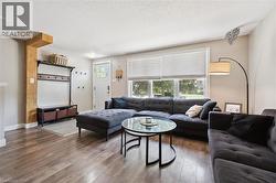 Bright living area featuring wood-finish flooring, a large multi-pane window, and a white entry door with glass inserts - 