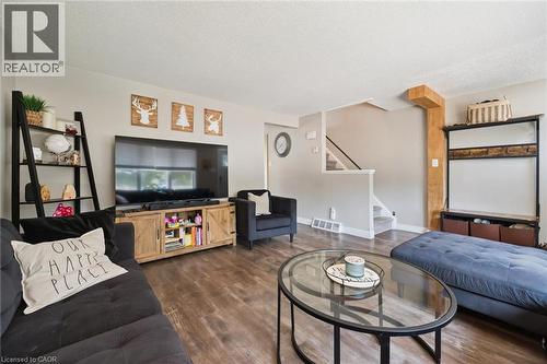Spacious living area featuring wood-finish flooring, light neutral wall paint, and a built-in staircase with carpeted treads - 589 Elgin Street N, Cambridge, ON - Indoor Photo Showing Living Room