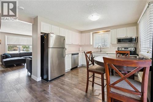 Kitchen featuring wood-finish flooring, white cabinetry, stainless steel appliances, and a tiled backsplash - 589 Elgin Street N, Cambridge, ON - Indoor Photo Showing Kitchen