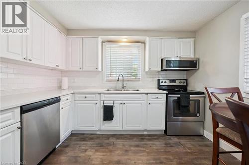 Modern kitchen featuring white shaker-style cabinetry, a white subway tile backsplash, and light-toned countertops - 589 Elgin Street N, Cambridge, ON - Indoor Photo Showing Kitchen With Double Sink