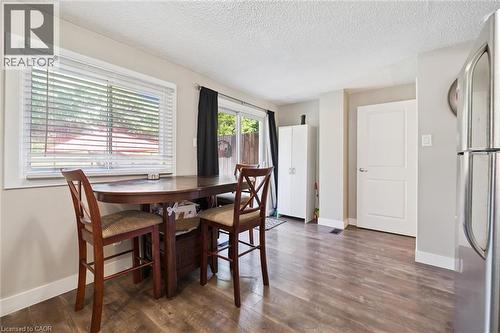 Bright dining area featuring wood-finish flooring, a large window with blinds, and a sliding glass door - 589 Elgin Street N, Cambridge, ON - Indoor Photo Showing Dining Room