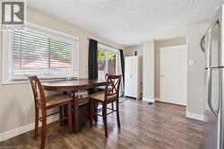 Bright dining area featuring wood-finish flooring, a large window with blinds, and a sliding glass door - 