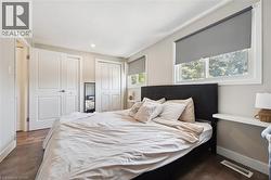 Spacious room featuring wood-finish flooring, two large windows with roller shades, recessed lighting, and ample closet space with bi-fold doors - 