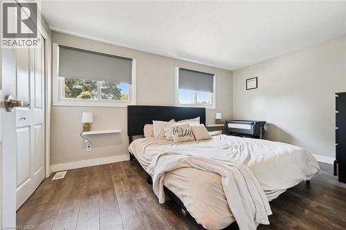 Bedroom featuring wood-finish flooring, two large windows with roller shades, and light-toned walls - 589 Elgin Street N, Cambridge, ON - Indoor Photo Showing Bedroom