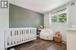 Interior room featuring wood-finish flooring, a window with white trim, and a prominent accent wall - 