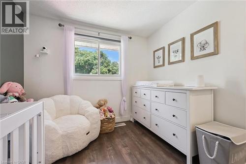 Room with wood-finish flooring, a white trim window, and white walls complemented by an accent wall - 589 Elgin Street N, Cambridge, ON - Indoor Photo Showing Bedroom