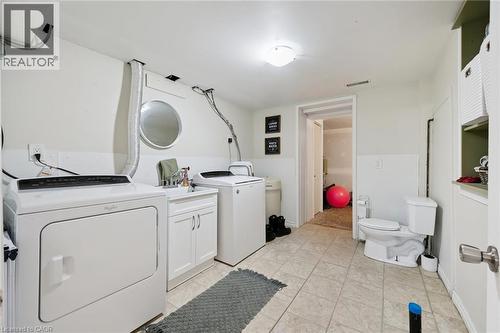 Dedicated laundry space featuring a white top-load washer, a white dryer, and a utility sink with white cabinetry - 589 Elgin Street N, Cambridge, ON - Indoor Photo Showing Laundry Room