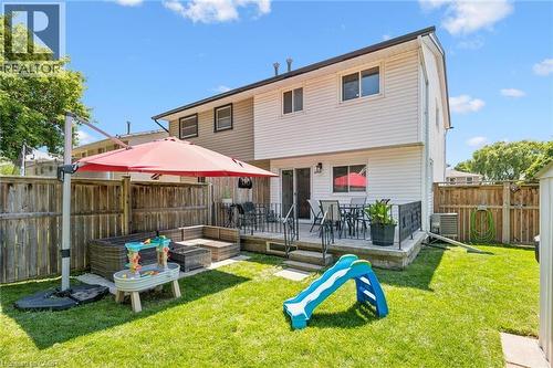 Fenced backyard featuring a raised deck with patio space, established lawn, and wooden privacy fencing - 589 Elgin Street N, Cambridge, ON - Outdoor