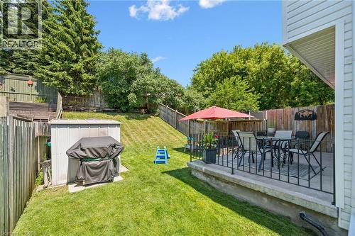 Spacious backyard featuring a concrete patio with black metal railings, a manicured lawn, an outdoor storage shed, and mature trees providing natural screening - 589 Elgin Street N, Cambridge, ON - Outdoor