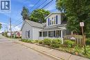 Light blue siding exterior featuring a covered front porch with white railing, blue window shutters, and mature trees - 153 Montrose Street N, Cambridge, ON  - Outdoor 
