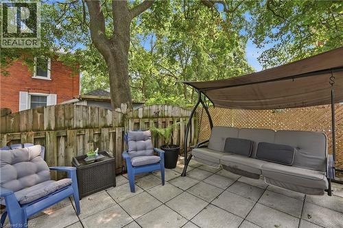 Paved patio area featuring large format square pavers, a wooden privacy fence, and mature trees providing overhead shade - 153 Montrose Street N, Cambridge, ON - Outdoor With Exterior
