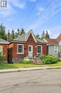 Brick exterior featuring a gabled roofline and a front porch with metal railings - 