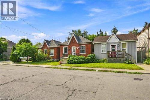 Brick and siding exterior featuring gabled rooflines, a front porch with wooden railings, and mature landscaping - 58 Edinburgh Avenue, Hamilton, ON - Outdoor With Facade