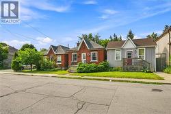 Brick and siding exterior featuring gabled rooflines, a front porch with wooden railings, and mature landscaping - 