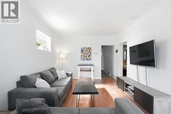 Bright living space featuring warm wood-finish flooring, white painted walls, and a window providing natural light - 