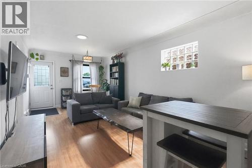 Bright living area featuring wood-finish flooring, a decorative glass entry door, and a glass block window - 58 Edinburgh Avenue, Hamilton, ON - Indoor Photo Showing Living Room