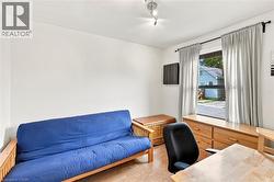 Room featuring light wood-finish flooring, white walls, and a window with light gray drapery - 
