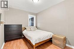 Bedroom featuring wood-finish flooring, a window with trim, and a ceiling-mounted light fixture - 