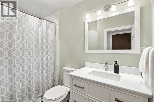 Bathroom featuring a white vanity with integrated sink, chrome faucet, white framed mirror, and a four-light fixture - 58 Edinburgh Avenue, Hamilton, ON - Indoor Photo Showing Bathroom