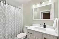 Bathroom featuring a white vanity with integrated sink, chrome faucet, white framed mirror, and a four-light fixture - 